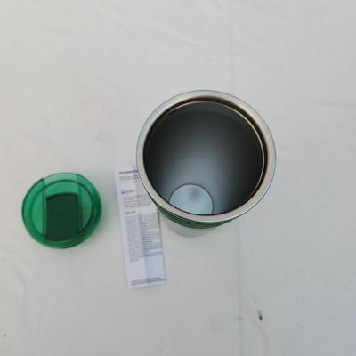 Sale Photo Thumbnail #234: A green stainless steel insulated travel tumbler with a matching lid. Designed for maintaining beverage temperatures. Includes an instruction or care sheet. The tumbler features a stainless steel interior and a green exterior with a silicone grip band for