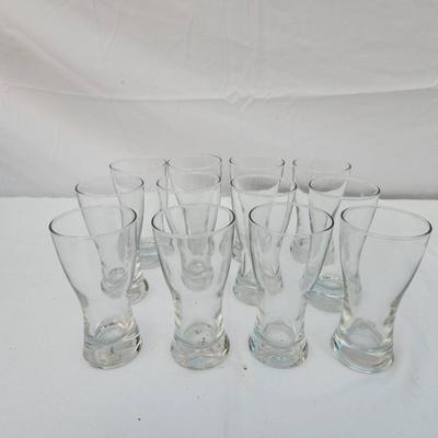 Sale Photo Thumbnail #241: 10 identical clear glass tumbler-style glasses with a curved design and slightly flared rim. Each glass features a weighted base for stability. Great for serving beverages. All glasses are in good condition with no visible chips or cracks.