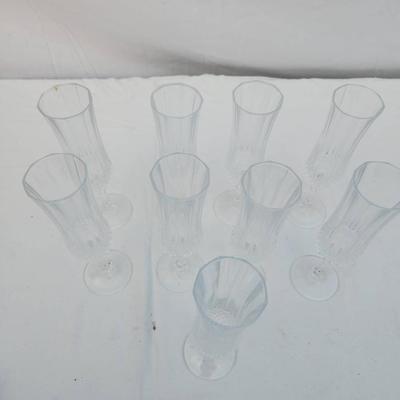 Sale Photo Thumbnail #249: Eight clear crystal champagne flute glasses with intricate cut designs on the stems and faceted detailing. Each flute features an elegant, elongated bowl ideal for serving champagne or sparkling wines. Condition appears to be good with no visible chips or