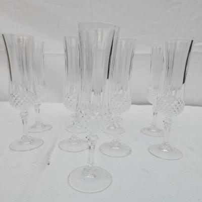 Sale Photo Thumbnail #247: Eight clear crystal champagne flute glasses with intricate cut designs on the stems and faceted detailing. Each flute features an elegant, elongated bowl ideal for serving champagne or sparkling wines. Condition appears to be good with no visible chips or