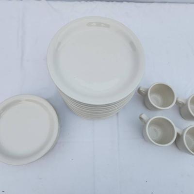 Sale Photo Thumbnail #280: 22 white ceramic items, including 15 rounded, stackable plates, 7 saucers, and 4 matching coffee cups with handles. Designed for durability and frequent use, suitable for both commercial and home settings. Uniform in design for seamless coordination.