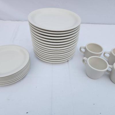 Sale Photo Thumbnail #279: 22 white ceramic items, including 15 rounded, stackable plates, 7 saucers, and 4 matching coffee cups with handles. Designed for durability and frequent use, suitable for both commercial and home settings. Uniform in design for seamless coordination.