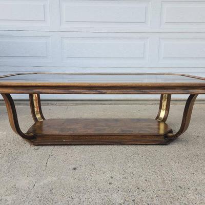 Sale Photo Thumbnail #295: Rectangular glass-top coffee table featuring an octagonal beveled edge and a solid wood frame with a rich finish. The base showcases brass accents and a wood lower shelf with a decorative veneer. Sturdy construction combines materials for a sophisticated 