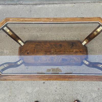 Sale Photo Thumbnail #294: Rectangular glass-top coffee table featuring an octagonal beveled edge and a solid wood frame with a rich finish. The base showcases brass accents and a wood lower shelf with a decorative veneer. Sturdy construction combines materials for a sophisticated 