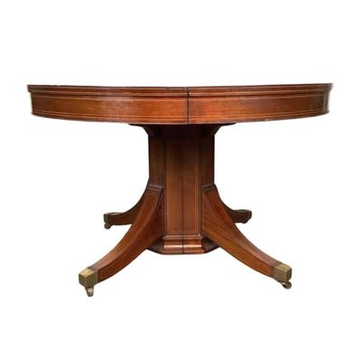 Sale Photo Thumbnail #1594: This magnificent round dining table, crafted from rich mahogany, offers both elegance and versatility for any dining space. The tabletop showcases a beautifully executed striped inlay design radiating from the center, adding a touch of refined detail and 