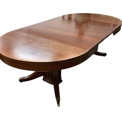 Sale Photo Thumbnail #1595: This magnificent round dining table, crafted from rich mahogany, offers both elegance and versatility for any dining space. The tabletop showcases a beautifully executed striped inlay design radiating from the center, adding a touch of refined detail and 