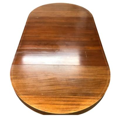 Sale Photo Thumbnail #1597: This magnificent round dining table, crafted from rich mahogany, offers both elegance and versatility for any dining space. The tabletop showcases a beautifully executed striped inlay design radiating from the center, adding a touch of refined detail and 