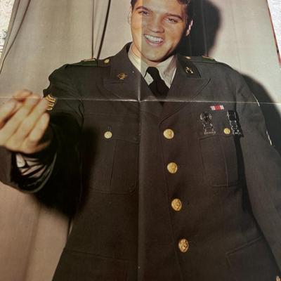 Sale Photo Thumbnail #430: Side one of poster shows Elvis Presley in his United States Army uniform, with the text "Elvis in the Army" visible. 
Side two Elvis and Priscilla Presley cutting their six-tier wedding cake. They were married on May 1, 1967 at the Aladdin Hotel in Las Ve