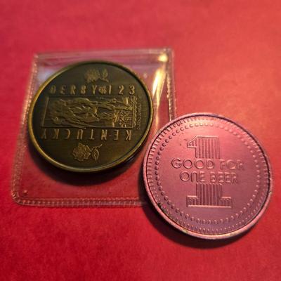 Sale Photo Thumbnail #47: This auction lot is for a grouping of Kentucky Derby Coins. This a pair of Kentucky Derby Coins.  The bronze colored coin is commemorating the 1997 Running of the Roses and come with its own plastic envelope.  The purple coin is a 1986 beer token.  It fee