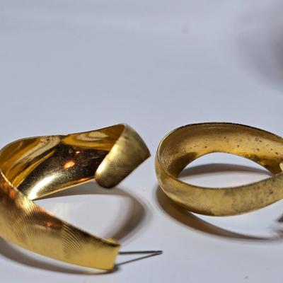 Thick gold toned necklace chain with several gold toned earrings and a bangle bracelet