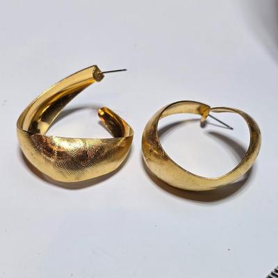 Thick gold toned necklace chain with several gold toned earrings and a bangle bracelet