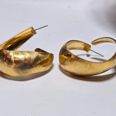 Thick gold toned necklace chain with several gold toned earrings and a bangle bracelet