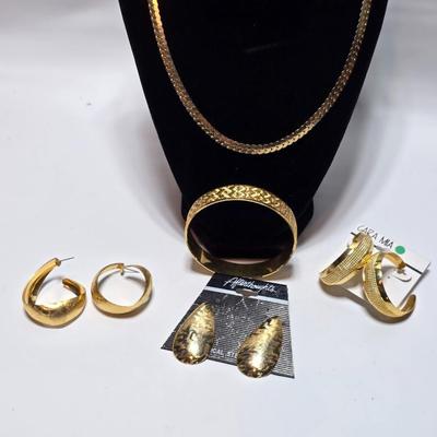 Thick gold toned necklace chain with several gold toned earrings and a bangle bracelet