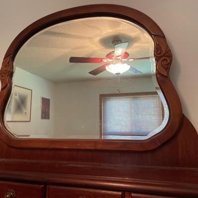 Tall wood dresser with mirror and shell design on doors