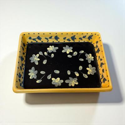 Sale Photo Thumbnail #431: Rectangle Ceramic Baking Dish yellow with blue polka dots on the rim and has a floral design on a dark background in the center
Approximately 10.5" X 8"