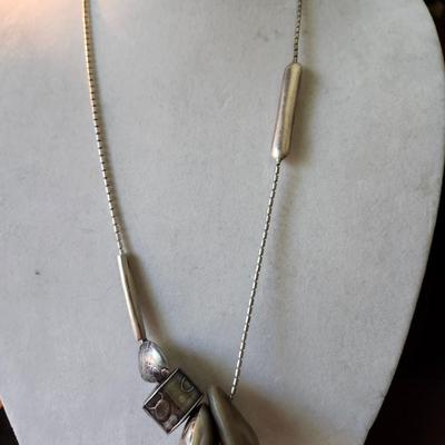 Sale Photo Thumbnail #169: 1989   30 Inch necklace with embossed pillow charms, hollow fabricated silver forms.  Signed.  
Her jewelry has SOLD prices ranging from $450 to $1150