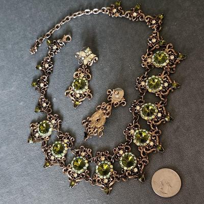 Sale Photo Thumbnail #276: This is a visually stunning set of jewelry.  Olive green rhinestones are set in an antique
bronze tone setting of ornate metalwork.  This is a statement necklace.
The matching pierced earrings complete the vision.
Enjoy!!!