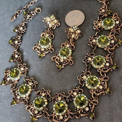 Sale Photo Thumbnail #275: This is a visually stunning set of jewelry.  Olive green rhinestones are set in an antique
bronze tone setting of ornate metalwork.  This is a statement necklace.
The matching pierced earrings complete the vision.
Enjoy!!!