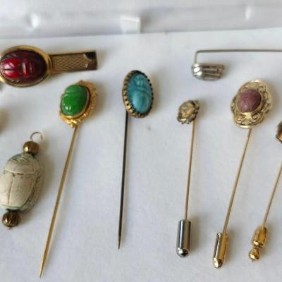 Sale Photo Thumbnail #314: Tie clasps, stick pins, and pendant collection of scarabs in various stones and metals.