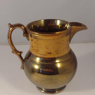 Sale Photo Thumbnail #606: Antique English Lusterware Pitcher- Copper Color with Cream Band- Approx 6" Tall.  Small chip on bottom of handle.