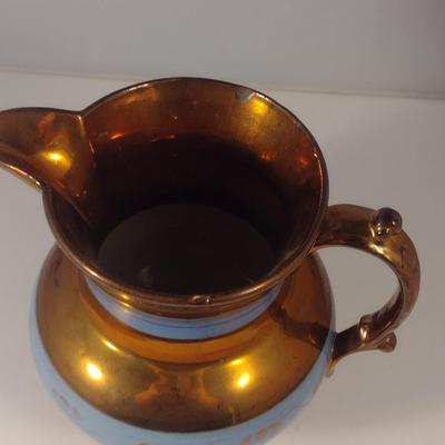 Sale Photo Thumbnail #619: Antique English Lusterware Pitcher- Copper Color with Blue Bands- Approx 6 1/2" Tall.  Item has chipping on rim and spout- please see all pictures.