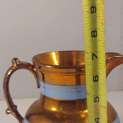 Sale Photo Thumbnail #623: Antique English Lusterware Pitcher- Copper Color with Blue Bands- Approx 6 1/2" Tall.  Item has chipping on rim and spout- please see all pictures.