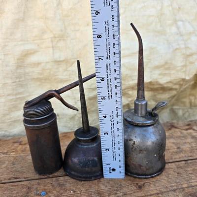 Three vintage metal oil cans with spouts and a metal tray