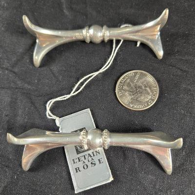 Sale Photo Thumbnail #107: This auction lot is for a Pair of Polished Pewter Knife Rests. This a nicely executed Pair of Knife Rests.  They were produced by L'Etain A La Rose.  These were originally sold in fine china shops.  They are very useful in keeping used knives off of the f