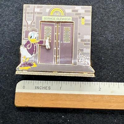 Sale Photo Thumbnail #18: Pin in very good condition. This Disney trading pin features Donald Duck, Mickey Mouse, and Minnie Mouse in a scene inspired by The Twilight Zone Tower of Terror attraction. 
The pin is a diorama-style pin, with Donald dressed as a bellhop leading Mickey 