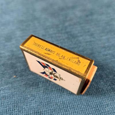 Sale Photo Thumbnail #170: This auction lot is for a WWII British War Relief Match Society Holder. It is brass and enamel with the cardboard match drawer inside.  The one side is engraved - "There will always be an England".  It is in good used condition and contains no matches.