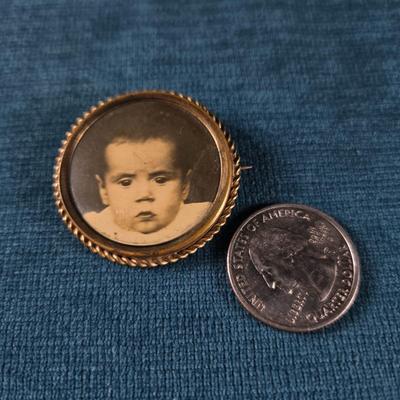 Sale Photo Thumbnail #178: This auction lot is for a Victorian Mourning Broach - #1. This is a very special Victorian Mourning Broach of a baby.  It is nicely framed in a brass broach case with a glass cover that is about  1-3/8-inches in diameter.  It is in very good condition for
