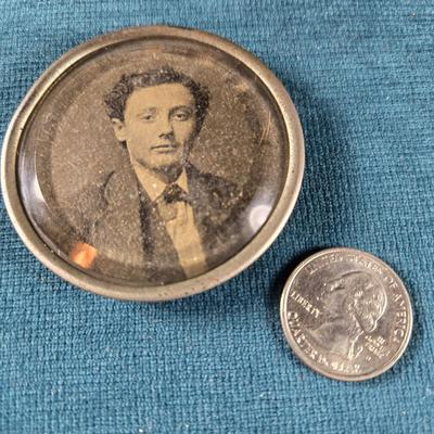 Sale Photo Thumbnail #184: This is a Victorian Mourning Broach Style Framed Tin Type.  It is of a middle age gentleman.  The glass cover is thick and has a deep bevel to it.  The frame is maybe silver plate.  There is no pin on the back to make it a broach, plus it is larger that m