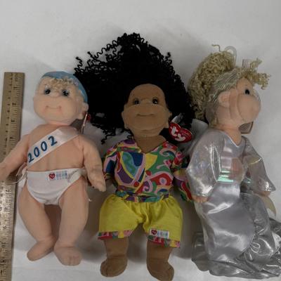 Sale Photo Thumbnail #135: The doll on the left is a "New Year 2002" Beanie Kid, wearing a diaper with "2002" written on a sash. 
The doll in the center is named Calypso, and she has black curly hair and is wearing a colorful shirt and yellow shorts. 
The doll on the right is aname