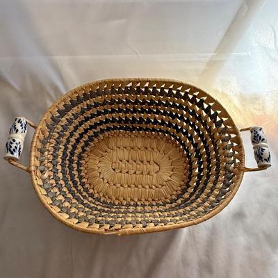 Sale Photo Thumbnail #79: Handwoven wicker basket with blue and white ceramic handles.