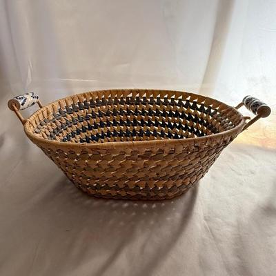 Sale Photo Thumbnail #80: Handwoven wicker basket with blue and white ceramic handles.