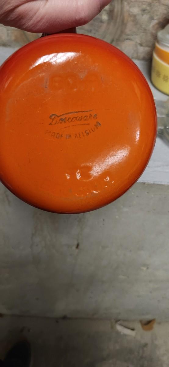 Sale Photo Thumbnail #404: That flame sauce pan enamel over cast with a wooden handle. A couple of pyrex pieces, some vintage lids etc