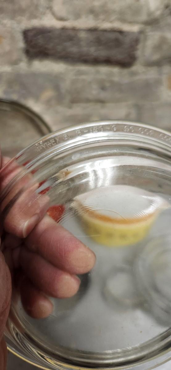 Sale Photo Thumbnail #397: That flame sauce pan enamel over cast with a wooden handle. A couple of pyrex pieces, some vintage lids etc