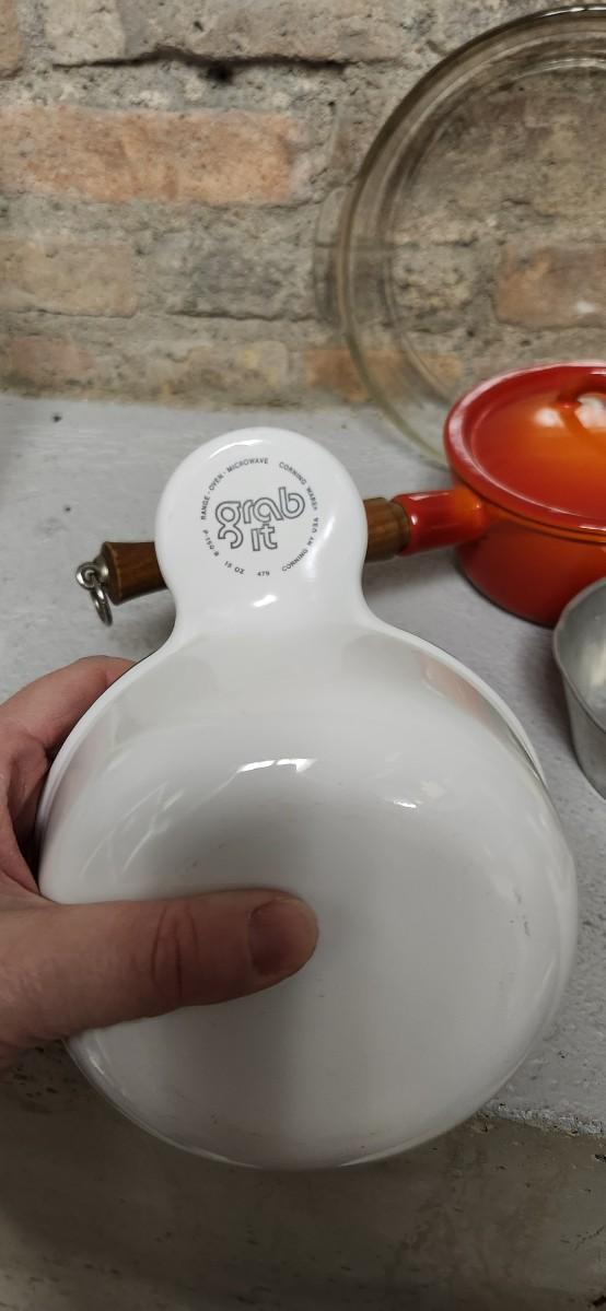 Sale Photo Thumbnail #395: That flame sauce pan enamel over cast with a wooden handle. A couple of pyrex pieces, some vintage lids etc