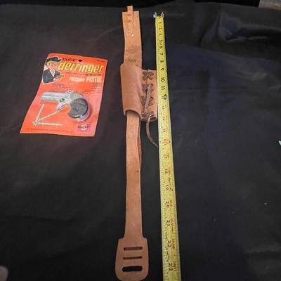 TOY DERRINGER SEALED ON BOARD AND A CHILD'S LEATHER BULLET BELT