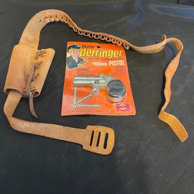 TOY DERRINGER SEALED ON BOARD AND A CHILD'S LEATHER BULLET BELT