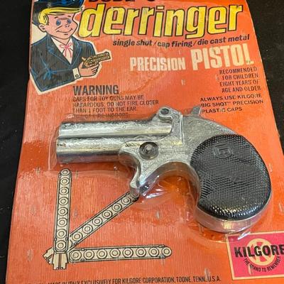 TOY DERRINGER SEALED ON BOARD AND A CHILD'S LEATHER BULLET BELT