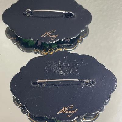 Painted wood pins are both signed