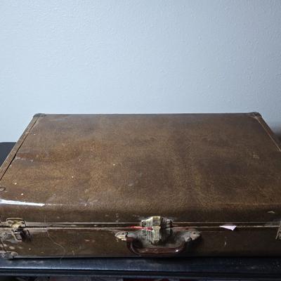 Tin sided luggage with an assortment of vintage children's clothes and baby quilt