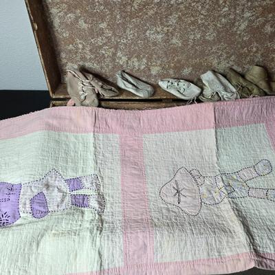 Tin sided luggage with an assortment of vintage children's clothes and baby quilt