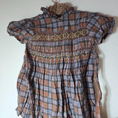 Tin sided luggage with an assortment of vintage children's clothes and baby quilt