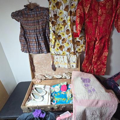 Tin sided luggage with an assortment of vintage children's clothes and baby quilt