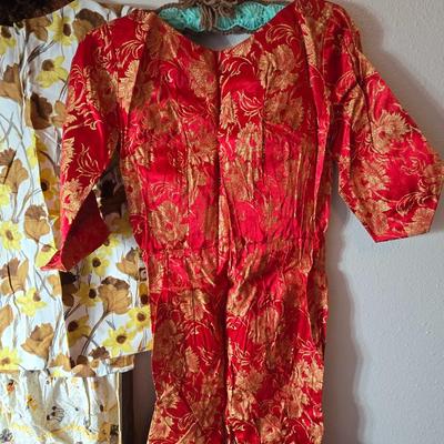 Tin sided luggage with an assortment of vintage children's clothes and baby quilt