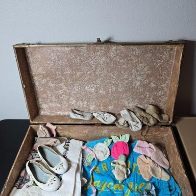 Tin sided luggage with an assortment of vintage children's clothes and baby quilt