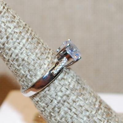 Size 6 Single Round Clear Stone Ring with Faint Line Accents on a Silver Tone Band (3.4g)