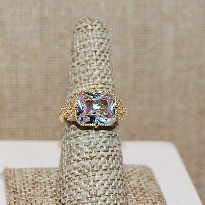 Size 7 Large Beveled Clear Glass Style Stone Ring with Triple Stone Side Accents on a Gold Tone Band (5.3g)
